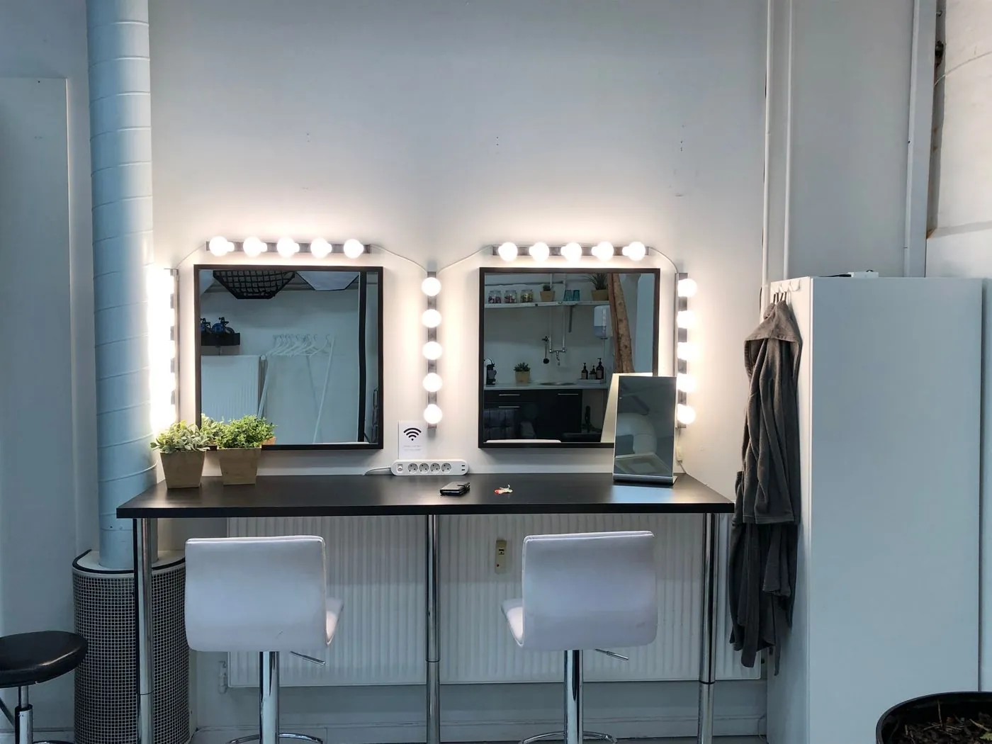 A beauty studio with a lit mirror station and stool